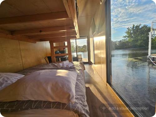 two beds in a room with a large window at Flotel Montebello in Montebello