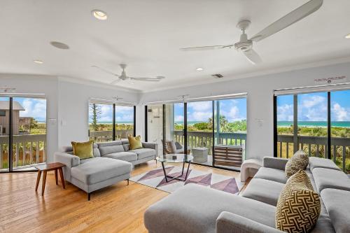 a living room with couches and chairs and windows at Just Beachy By Beachside Management in Siesta Key