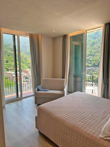 a bedroom with a bed and a chair and windows at Cloud Nine in Riomaggiore