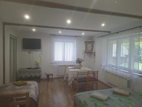 a room with two beds and a table and a television at Agroturystyka Przy Rajskim Sadzie in Nowy Berezów