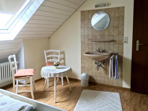 ein Badezimmer mit einem Waschbecken, einem Tisch und einem Stuhl in der Unterkunft Gästehaus Hoffmann in Detzem