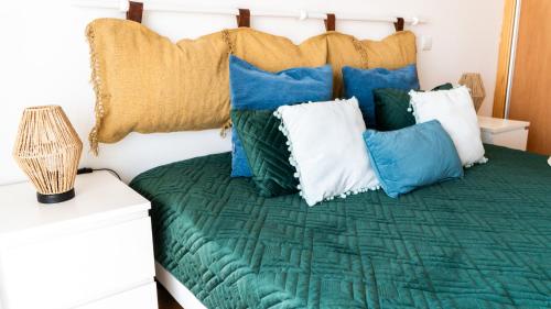 Un dormitorio con una cama con almohadas azules y verdes. en Pandora House, en Nazaré