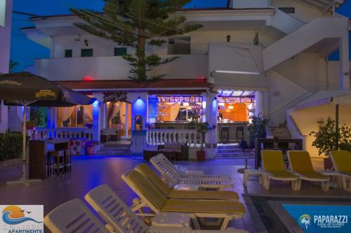 a resort with lounge chairs and a bar at night at Chandris Apartments in Kavos