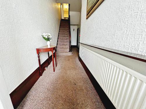 a hallway with a table with a vase of flowers on it at Affordable and Comfortable Guest House by Sea in Cleethorpes