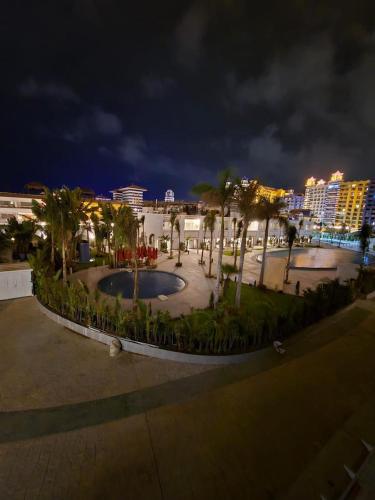 a park at night with palm trees and buildings at chalet porto marina pool view in El Alamein