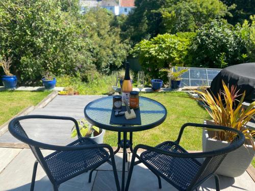 a table with a bottle of beer and two chairs at East Barn Garden View in Georgeham
