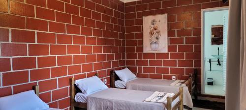 a room with two beds and a brick wall at Pousada Itatiba Holliday in Itatiba