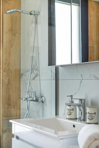 a white bathroom with a sink and a mirror at Mare Blue The Vintage Suite in Skala Rachoniou