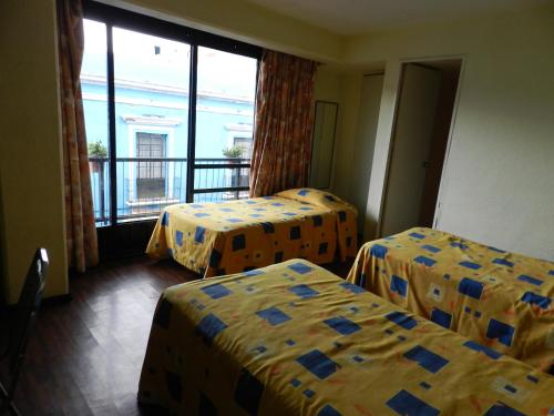 a hotel room with two beds and a balcony at Hotel San Miguel in Puebla