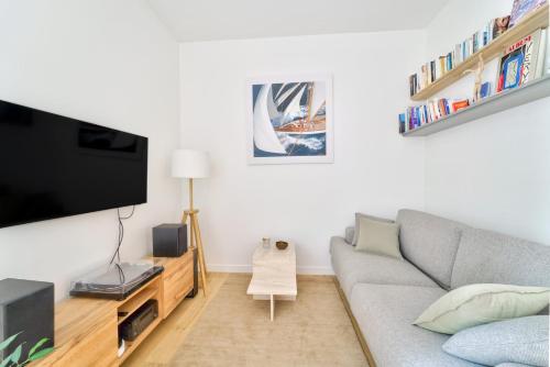 un salon avec un canapé et une télévision à écran plat dans l'établissement Parisian Charm, Modern & Quiet Studio, à Paris