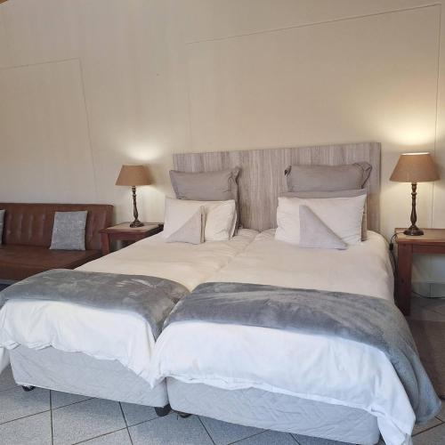 una cama grande con sábanas y almohadas blancas en Lyn's Self Catering, en Swakopmund