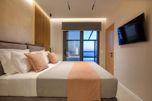 a bedroom with a bed with a flat screen tv at Thea Suites in Ouranoupoli