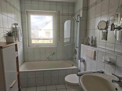 a bathroom with a tub and a toilet and a sink at Ferienwohnung mit Kanalblick in Hirschaid