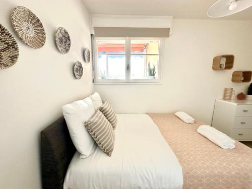 Un dormitorio con una cama con almohadas y una ventana. en Superbe 4 couchages avec terrasse - Clim - 50m de la mer, en Saint-Raphaël