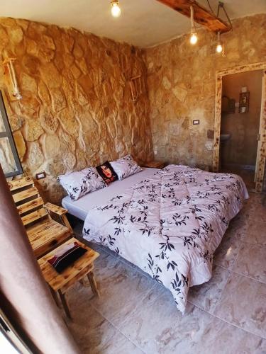 a bedroom with a bed and a stone wall at Friends of Dana Hotel in Dana