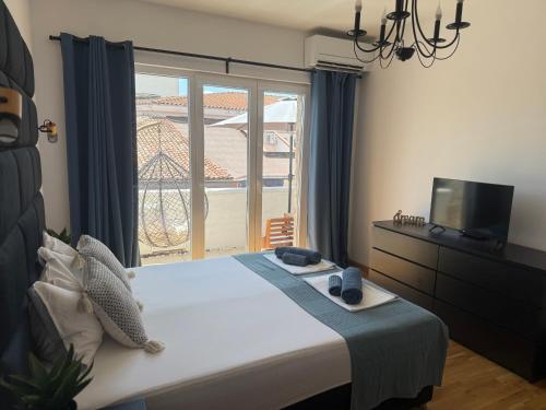 a bedroom with a bed and a tv and a window at Holiday Apartment ORA in Balchik