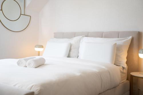 a white bed with white pillows and a mirror at Bijou D'or in Grenchen