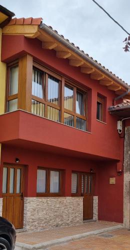 a red house with wooden doors and windows at Apartamentos Les Texuques in Nueva de Llanes