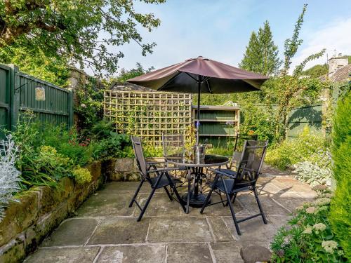 a table and chairs with an umbrella in a garden at Whibberley Cottage in Ashford
