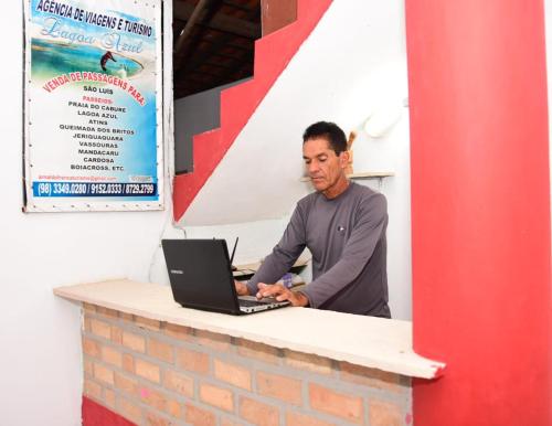 a man sitting at a counter with a laptop at Hostel da Lua in Barreirinhas