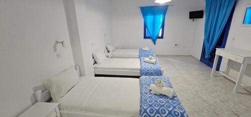 a small room with two beds and a blue curtain at Pleasure Black Beach Perissa Santorini in Perissa