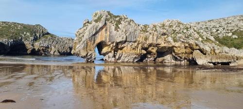 a rock formation in the water on a beach at Apartamentos Les Texuques in Nueva de Llanes