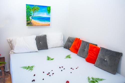 a white couch with colorful pillows and a painting on the wall at Studio privé climatisé en bas de villa in Fort-de-France