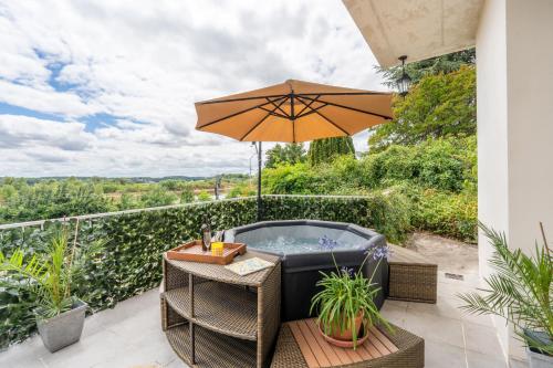 a patio with a hot tub and an umbrella at Appart 10personnes Terrasse vue Loire, Parkings Voitures Vélos,10min Centre Blois,40min Zoo Beauval in Blois