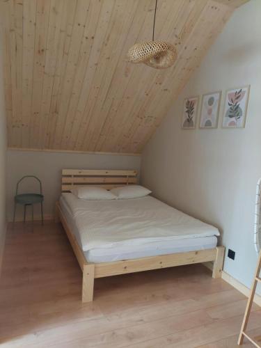 a bed in a room with a wooden ceiling at Dominickie Antresole in Boszkowo-Letnisko