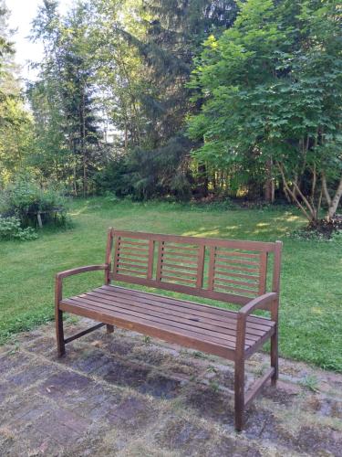 a wooden bench sitting on the grass in a park at Aalto A - A whole house with 5 bedrooms and a woodburning sauna in Oulu
