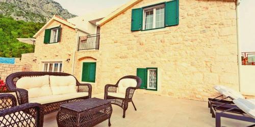 a patio with wicker chairs and a white couch at Steinhaus Villa Ane in Tučepi