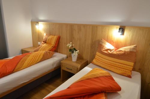 two beds in a small room with orange sheets at Villa Paröis in La Valle