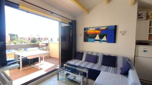 a living room with a couch and a balcony at Appartement T2 dans village Naturiste en bord de mer in Leucate-Plage