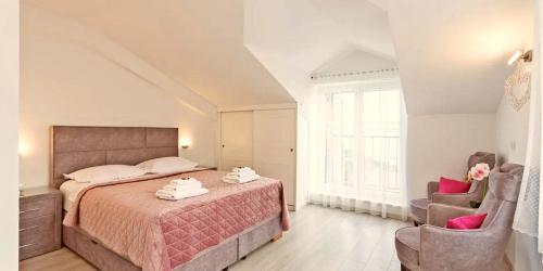 a bedroom with a large bed and two chairs at Steinhaus Villa Ane in Tučepi