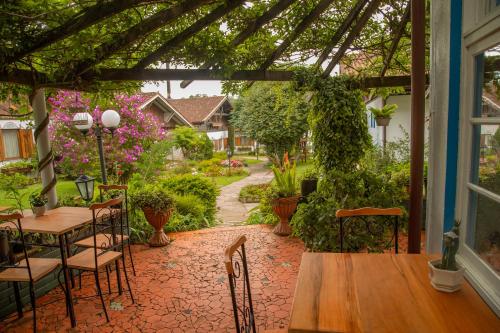 a patio with a table and chairs and a garden at Hotel Ritta Höppner in Gramado