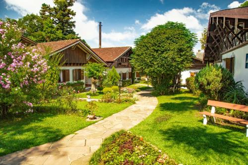 a garden with a wooden bench in front of a house at Hotel Ritta Höppner in Gramado