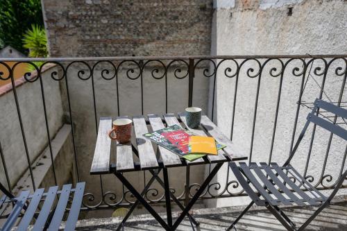 a table with two cups and a book on a balcony at Le jungle, hyper centre, balcon et terrasse in Tarbes
