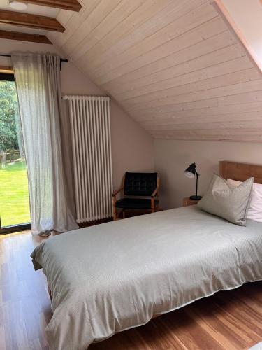 a bedroom with a large white bed and a chair at Bernātu Kalnmaļi in Bernāti