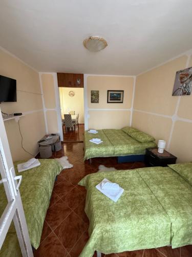 a room with three beds with green sheets at Apartman Marković in Meljine