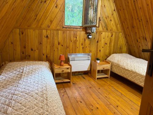 a bedroom with two beds and a window and wooden walls at Chata u Hagrida in Štrba