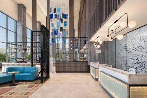 a lobby with blue furniture and large windows at Le Meridien Ahmedabad in Ahmedabad