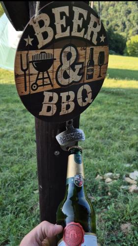 a person holding a bottle of beer and a sign at GLAMPING Považie in Trenčín