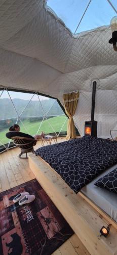 a bed in a tent with a view of a field at GLAMPING Považie in Trenčín