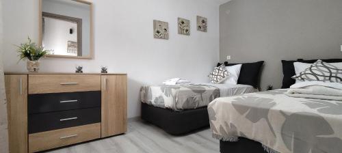 a bedroom with two beds and a dresser and a mirror at Modern House Close to the Sea Asprovalta in Asprovalta