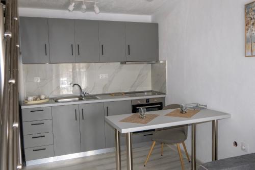 a kitchen with white cabinets and a table with two chairs at Modern House Close to the Sea Asprovalta in Asprovalta