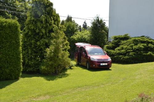 a red van parked in a yard next to trees at Vila Kateřina in Broumov