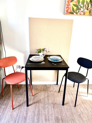 a black table with two chairs and a table with two plates at Studio confort proche de aéroport Paris-Orly in Villeneuve-le-Roi