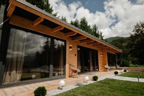 a house with large glass windows on a patio at Măgura Ținutul Lupilor in Colibiţa