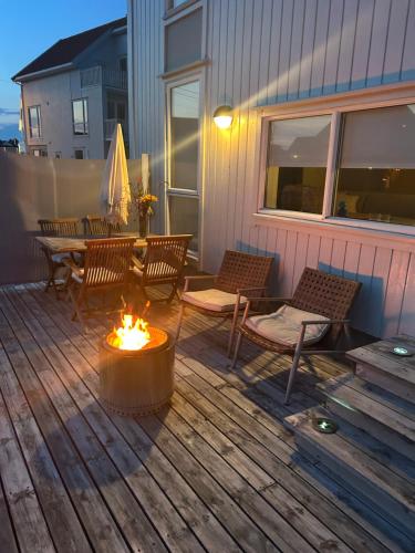 a deck with a table and chairs and a fire pit at Flott Leilighet, 1 etasje med nydelig sjøutsikt in Karmøy