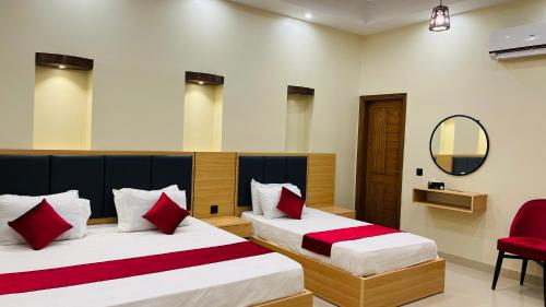 a bedroom with two beds with red pillows and a mirror at Hotel Karachi Guest House in Karachi